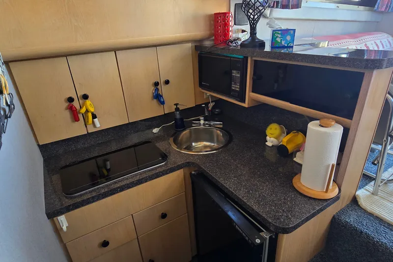Slide: The Image of Compact kitchen area in a 1989 Silverton 34 Convertible boat with modern amenities. - 23
