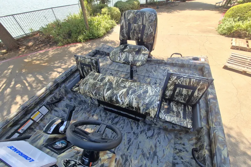 Slide: The Image of 2027 Ranger RB190 boat interior with camouflage seats and steering wheel, docked by a lakeside. - 10