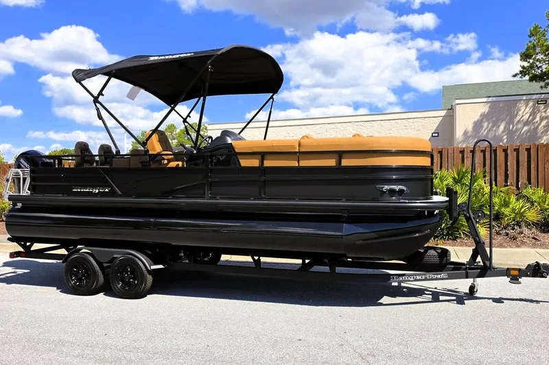 Slide: The Image of 2027 Ranger 220FC pontoon boat with black exterior and tan seating on a trailer. - 6