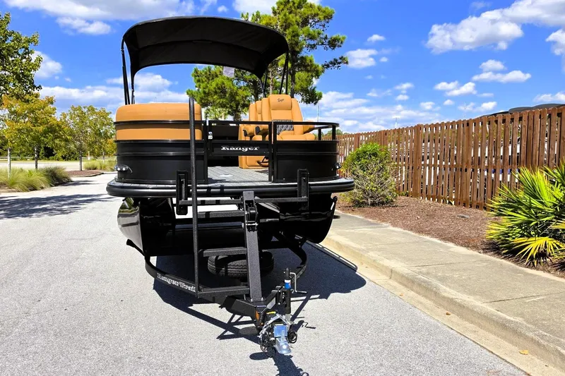 Slide: The Image of 2027 Ranger 220FC boat on trailer, parked on sunny street with trees and fence. - 9