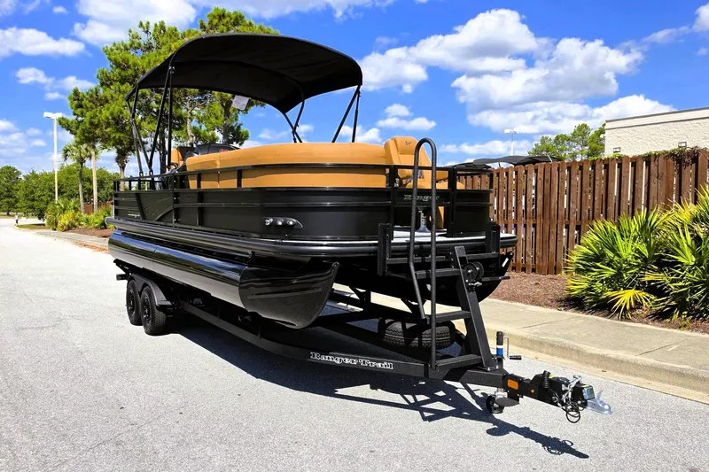 Slide: The Image of 2027 Ranger 220FC pontoon boat on trailer, parked outdoors under a clear blue sky. - 8