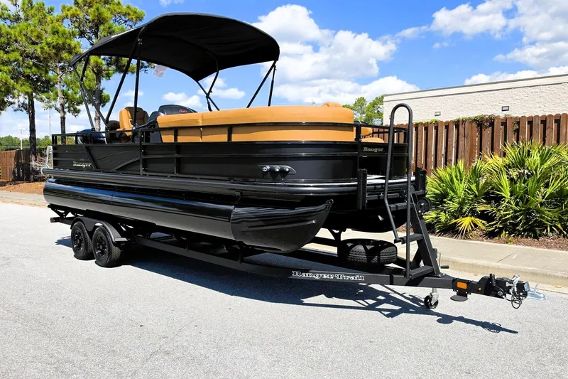 Slide: The Image of 2027 Ranger 220FC pontoon boat on trailer, parked outdoors under blue sky. - 7