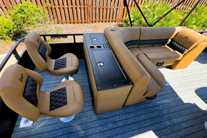 Slide: The Image of 2027 Ranger 220FC boat interior with tan seating and central console, surrounded by greenery. - 19