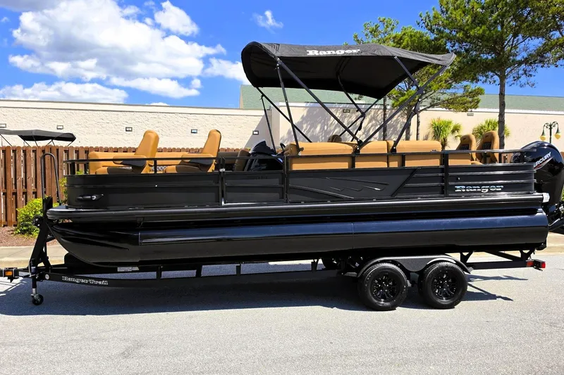 Slide: The Image of 2027 Ranger 220FC pontoon boat with canopy on trailer, parked outdoors under blue sky. - 11