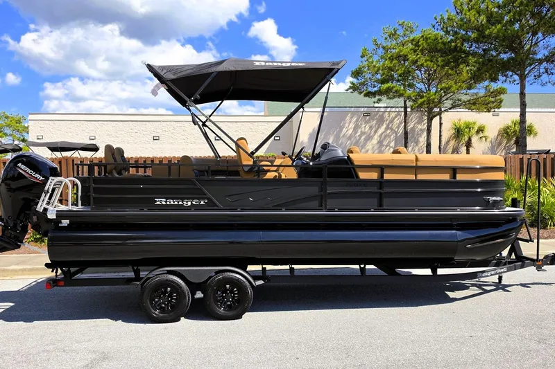 Slide: The Image of 2027 Ranger 220FC pontoon boat with canopy, parked on a trailer under a blue sky. - 1