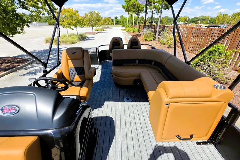Slide: The Image of 2027 Ranger 220FC boat interior with tan seating and steering console, parked outdoors. - 17