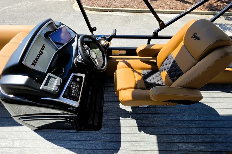 Slide: The Image of 2027 Ranger 220FC boat interior with tan and black captain's chair and modern dashboard. - 15