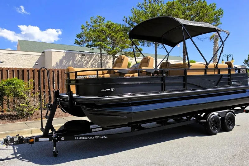 Slide: The Image of 2027 Ranger 220FC pontoon boat on trailer, parked outdoors under clear sky. - 12