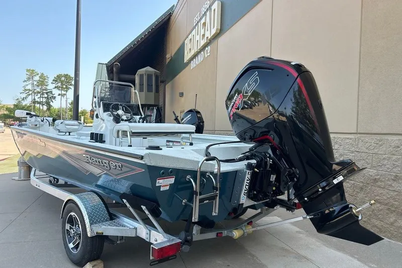 Slide: The Image of 2027 Ranger RB190 boat with powerful outboard motor on a trailer, parked outside a building. - 2