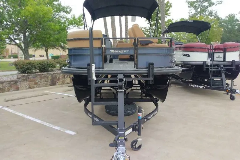 Slide: The Image of 2027 Ranger 223FC pontoon boat on trailer in parking lot, surrounded by trees. - 14