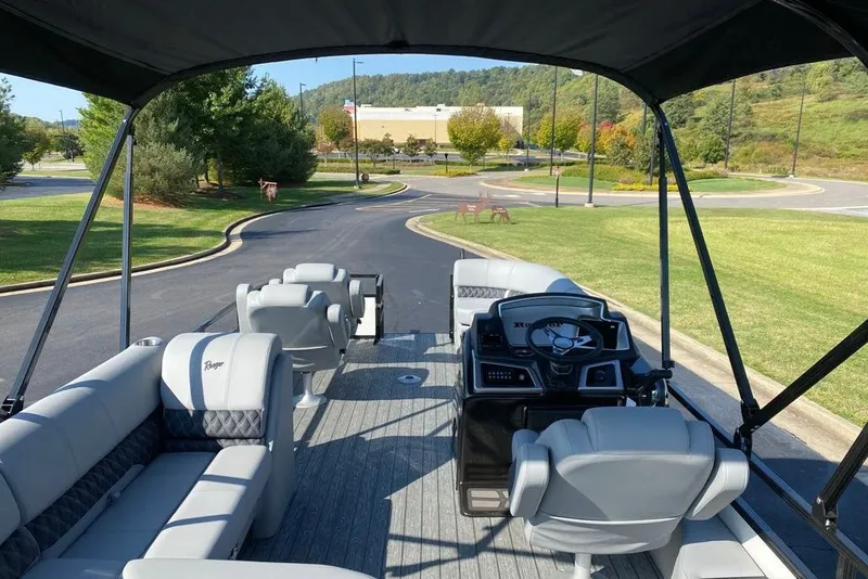 Slide: The Image of 2027 Ranger 220FC pontoon boat with spacious seating and modern helm, parked outdoors. - 5