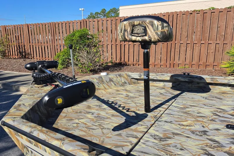 Slide: The Image of 2027 Ranger RB190 boat with camouflage seating and trolling motor, parked near wooden fence. - 19