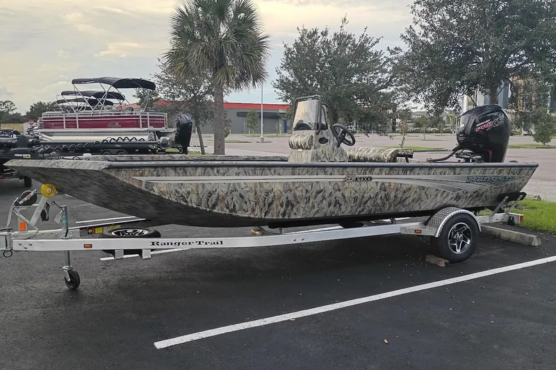 Slide: The Image of 2027 Ranger RB190 boat with camouflage design on a trailer in a parking lot. - 2