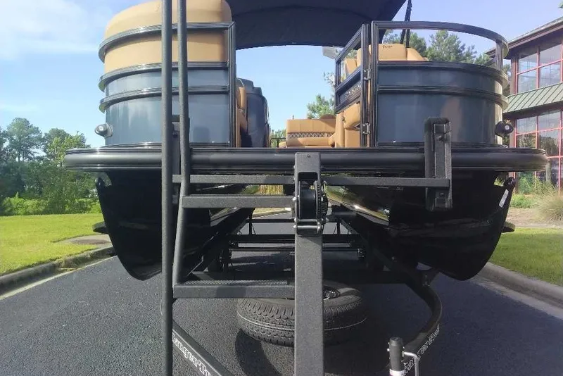 Slide: The Image of 2027 Ranger 220FC pontoon boat on trailer, parked on asphalt near green landscape. - 15