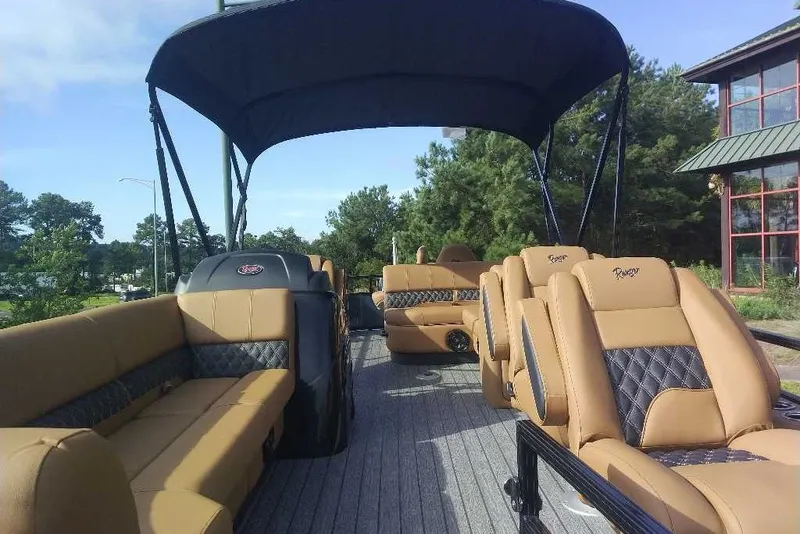 Slide: The Image of 2027 Ranger 220FC pontoon boat with tan seating and canopy, docked near trees. - 11