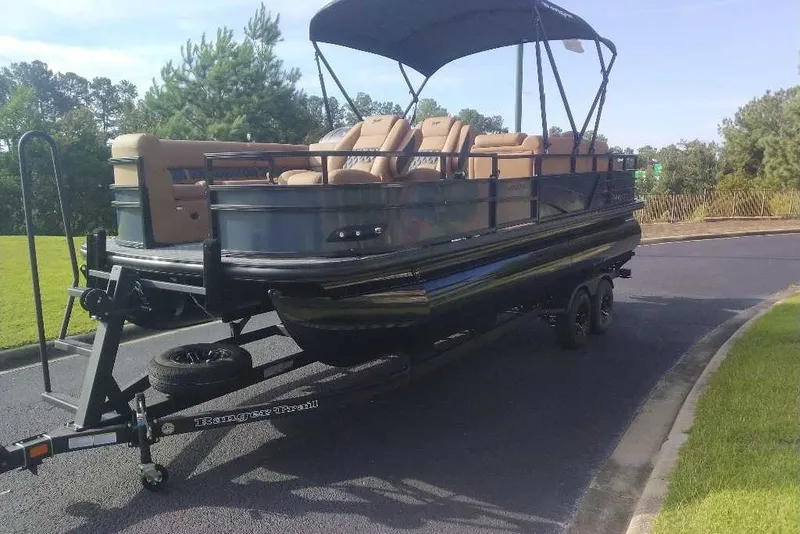 Slide: The Image of 2027 Ranger 220FC pontoon boat on trailer, parked on a sunny road. - 14