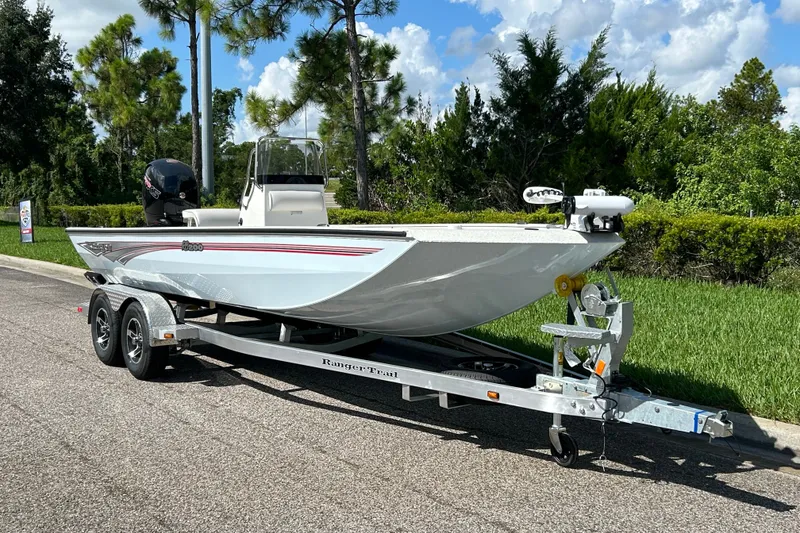 Slide: The Image of 2027 Ranger RB200 boat on trailer, parked on roadside with lush greenery background. - 2