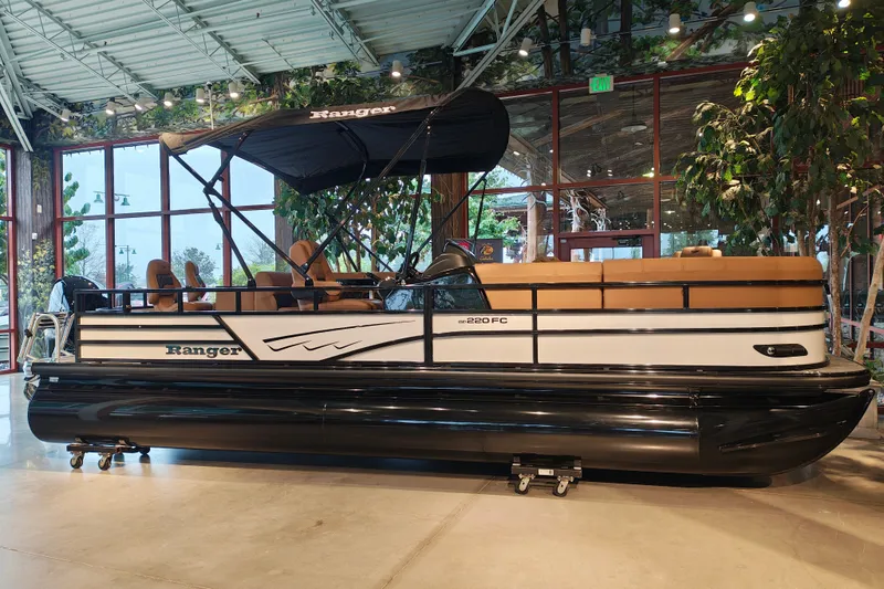 The Image of 2027 Ranger 220FC pontoon boat displayed indoors with canopy and seating. - 0