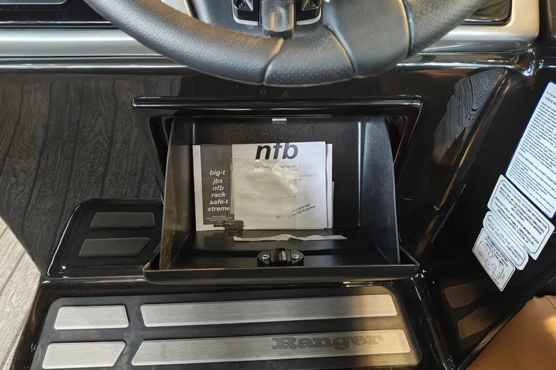 Slide: The Image of Open glove compartment in 2027 Ranger 220FC boat, showing documents and steering wheel. - 30