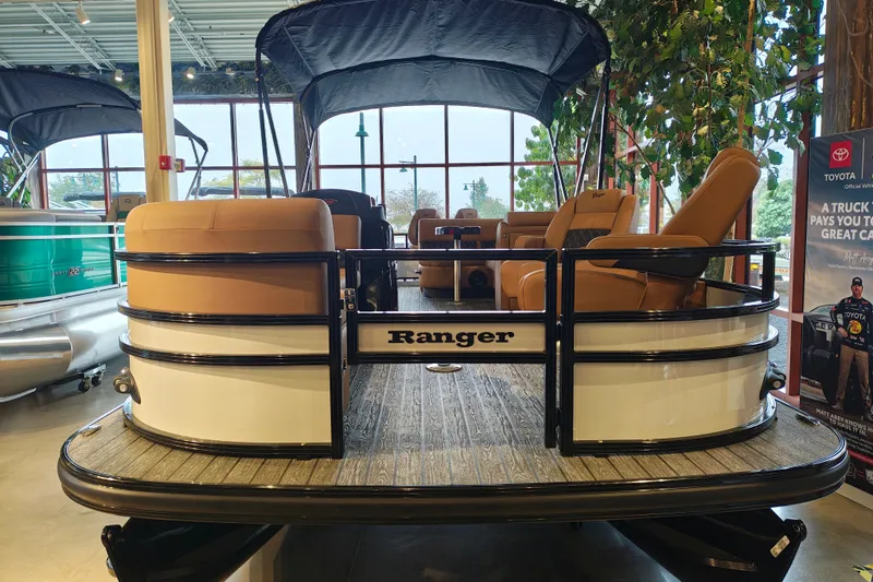 Slide: The Image of 2027 Ranger 220FC pontoon boat with tan seating, displayed indoors. - 3