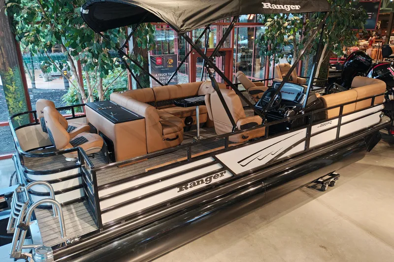 Slide: The Image of 2027 Ranger 220FC pontoon boat with tan seating and canopy in showroom display. - 4