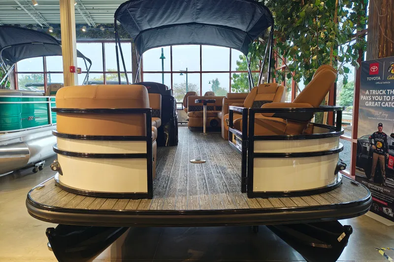 Slide: The Image of 2027 Ranger 220FC pontoon boat with tan seating, displayed indoors. - 2