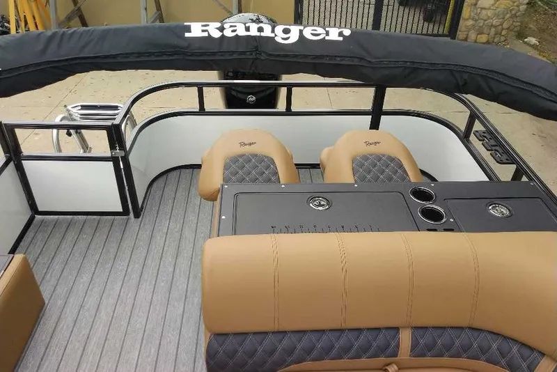 Slide: The Image of 2027 Ranger 220FC boat interior with tan and black seating, cup holders, and steering console. - 3