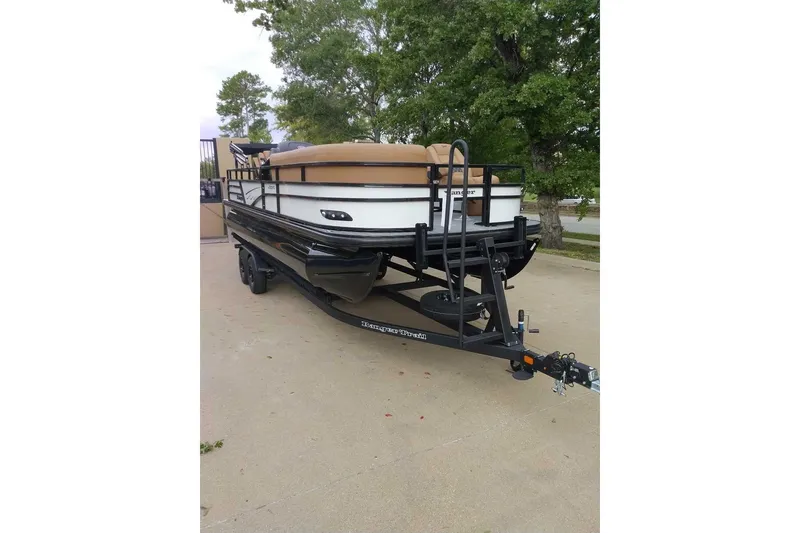 Slide: The Image of 2027 Ranger 220FC pontoon boat on trailer, parked outdoors near trees. - 1