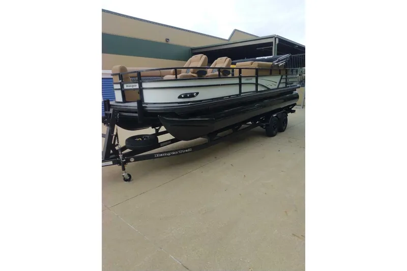 Slide: The Image of 2027 Ranger 220FC pontoon boat on trailer, parked outdoors. - 2