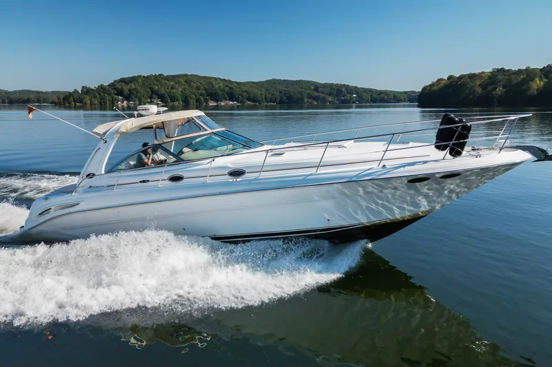 The Image of 2003 Sea Ray 410 Sundancer cruising on a serene lake under clear blue skies. - 0