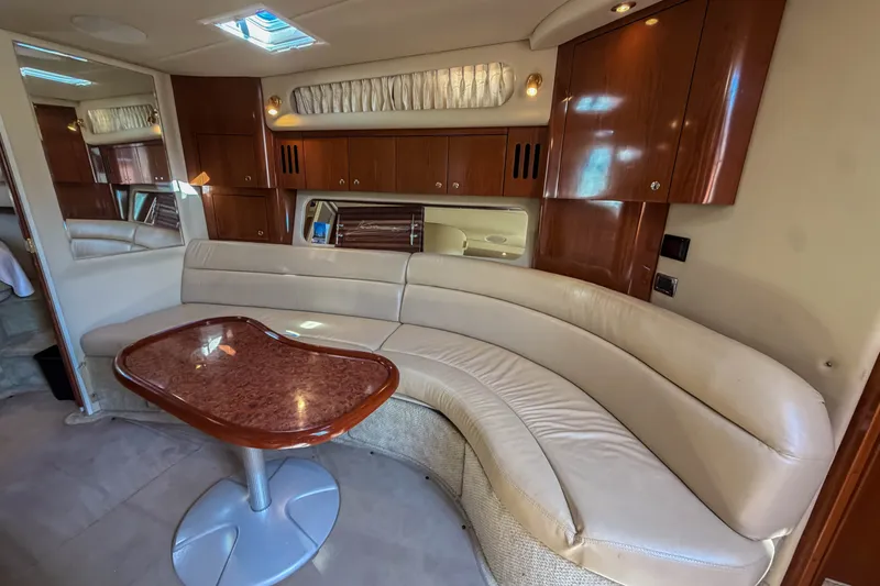 Slide: The Image of Luxurious interior of 2003 Sea Ray 410 Sundancer yacht with curved seating and wooden table. - 35