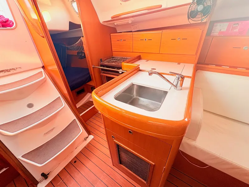 Slide: The Image of The interior of a 2007 Beneteau First 36.7 features a compact kitchen with a sink and stove. - 20