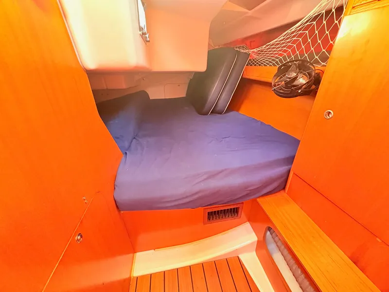 Slide: The Image of The cabin of a 2007 Beneteau First 36.7 with a blue bed and wooden features. - 21