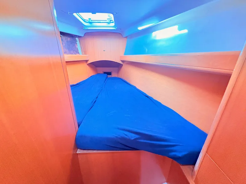 Slide: The Image of The cabin of the 2007 Beneteau First 36.7 features a cozy bed with blue bedding. - 16