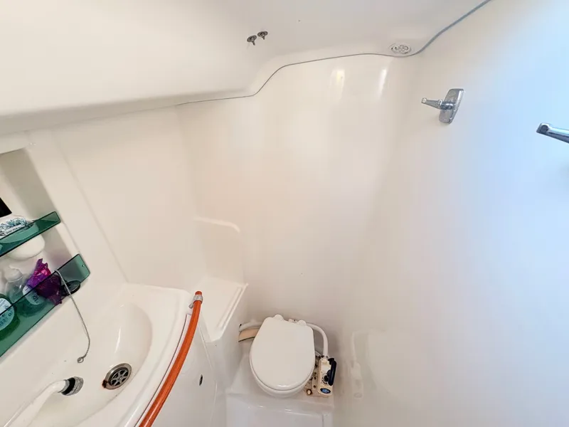 Slide: The Image of The image shows a clean, white bathroom on a boat with a sink and toilet. - 17