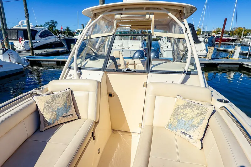 Slide: The Image of 2016 Grady-White Freedom 275 boat interior at marina, featuring comfortable seating and nautical-themed pillows. - 16