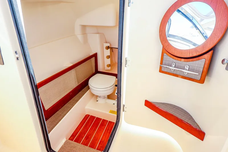 Slide: The Image of 2016 Grady-White Freedom 275 boat interior with toilet and round mirror. - 30