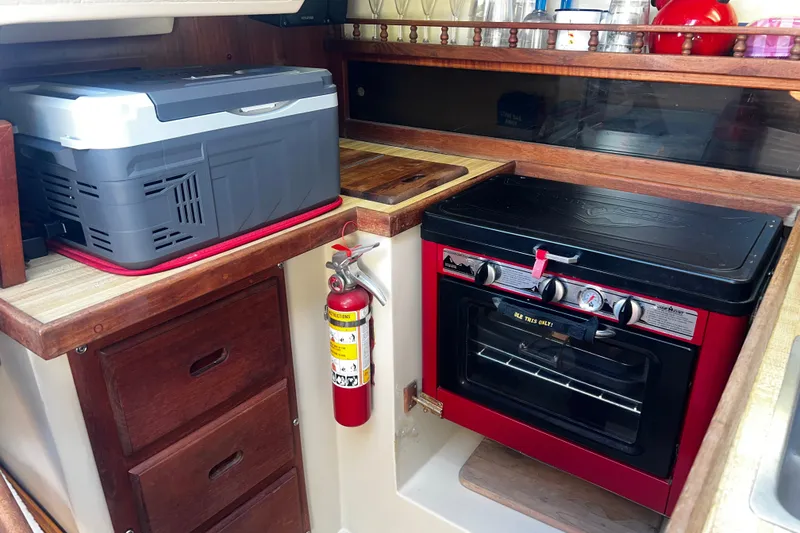 The Image of Compact kitchen in a 1983 Catalina 30 sailboat with stove, cooler, and fire extinguisher. - 0