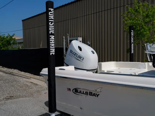 Slide: The Image of A Bulls Bay 2000 boat with a Suzuki engine, parked beside a building. - 38