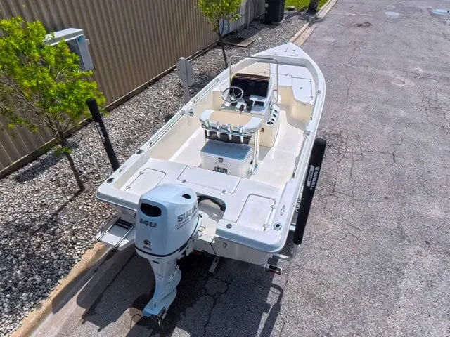Slide: The Image of A white Bulls Bay 2000 boat with Suzuki outboard motor, parked on a street beside a building. - 15
