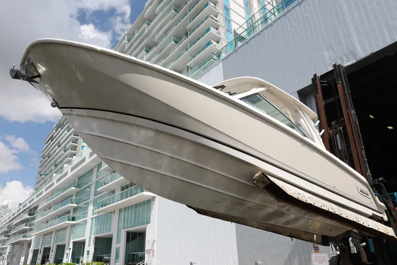 Slide: The Image of 2016 Boston Whaler 320 Vantage boat lifted near modern building, under blue sky. - 5