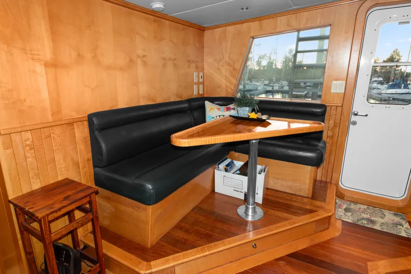 Slide: The Image of Interior of 2006 Solander Eclipse Steel Trawler with wooden dining area and black seating. - 13