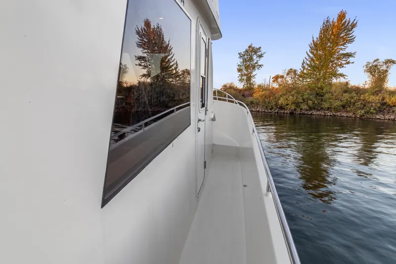 Slide: The Image of Side view of 2006 Solander Eclipse Steel Trawler on calm water near autumn trees. - 61