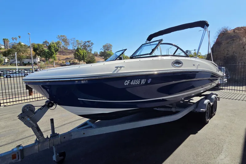 Slide: The Image of 2022 Bayliner VR6 Bowrider OB on trailer, parked outdoors under clear blue sky. - 1