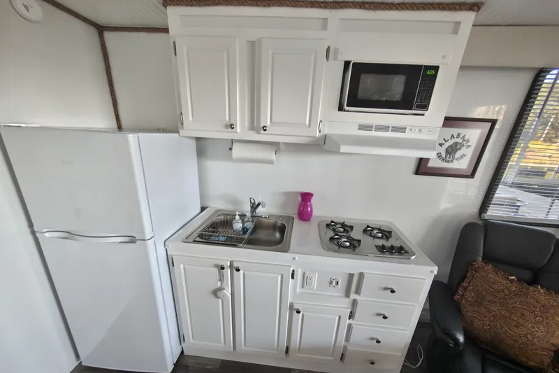 Slide: The Image of Compact kitchen in 2023 Catamaran Cruisers 1245 with stove, sink, fridge, and microwave. - 2