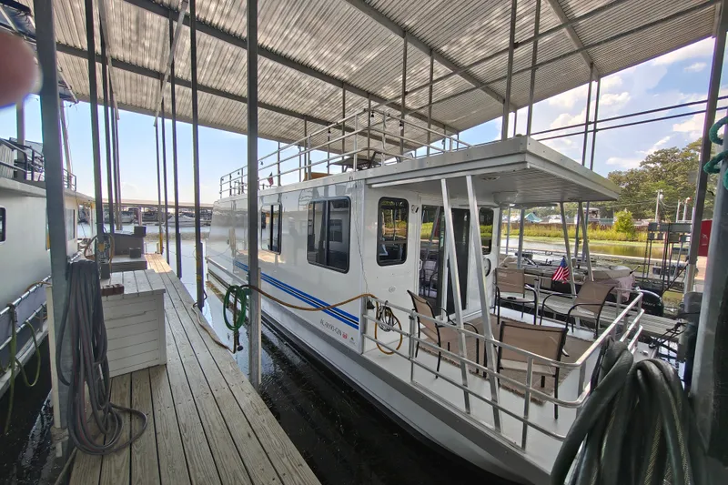 The Image of 2023 Catamaran Cruisers 1245 houseboat docked under a covered marina. - 11
