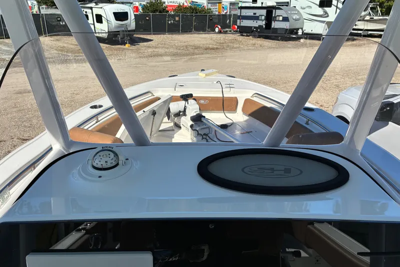Slide: The Image of 2023 Sea Hunt Ultra 229 boat interior with compass and seating, parked near RVs. - 45
