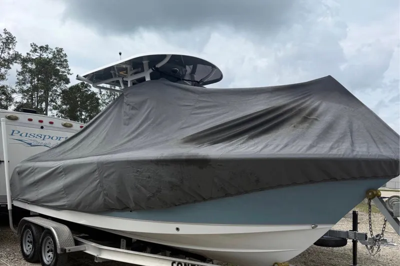 Slide: The Image of 2023 Sea Hunt Ultra 229 boat covered on trailer, parked outdoors under cloudy sky. - 2
