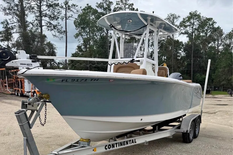 Slide: The Image of 2023 Sea Hunt Ultra 229 boat on trailer, parked outdoors with trees in background. - 1