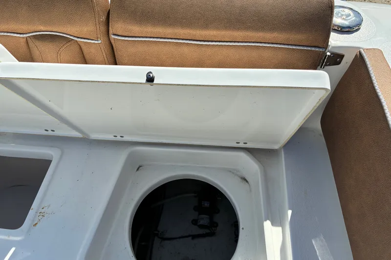 Slide: The Image of 2023 Sea Hunt Ultra 229 boat storage compartment with brown seating. - 65